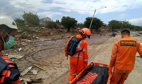 Dalam foto yang dibagikan BASARNAS, Sabtu (29/9), tampak petugas sedang memindahkan korban jiwa di Pantai Wina, setelah gempa dan tsunami terjadi di Kota Palu.