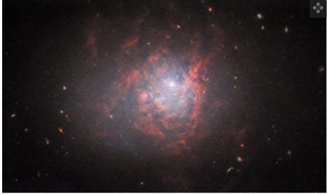 Dalam gambar baru yang diambil oleh Teleskop Luar Angkasa Hubble, galaksi kerdil NGC 1705 bersinar dalam awan cahaya terang dan awan merah.