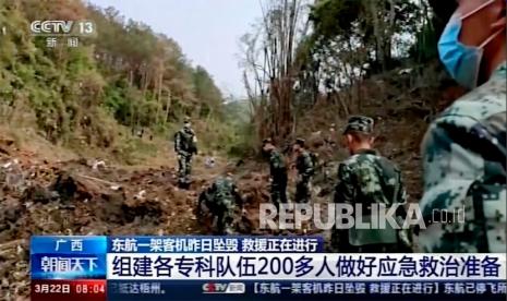  Dalam gambar yang diambil dari rekaman video yang dijalankan oleh CCTV China, tentara melakukan operasi pencarian di lokasi kecelakaan pesawat di Kabupaten Tengxian di Daerah Otonomi Guangxi Zhuang China selatan, Selasa, 22 Maret 2022. Dompet bernoda lumpur. kartu bank. Kartu identitas resmi. Beberapa barang pribadi dari 132 nyawa yang diduga hilang dijajarkan oleh petugas penyelamat yang menjelajahi lereng gunung terpencil pada hari Selasa untuk mencari puing-puing pesawat China Eastern yang satu hari sebelumnya secara misterius jatuh dari langit dan meledak menjadi bola api besar.