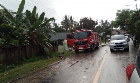 Damkar membersihkan Jalan Raya Anyer yang semalam berantakan tersapu tsunami, Ahad (23/12).