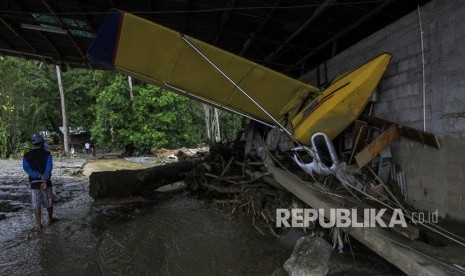 Dampak Banjir Bandang Sentani. Seorang warga berada di dekat pesawat latih yang terdampak banjir bandang di Sentani, Kabupaten Jayapura, Papua, Ahad (17/3/2019).