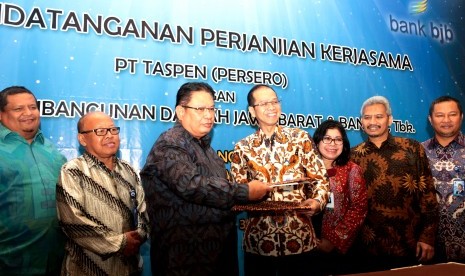  DANA PENSIUN -- Dirut Bank BJB Ahmad Irfan (keempat dari kanan) dan Dirut PT Taspen (Persero) Iqbal Latanro berjabat (ketiga dari kiri) bertukar berkas perjanjian kerja sama yang baru saja ditandatanganinya di Crown Plaza, Jakarta, Rabu (30/9).