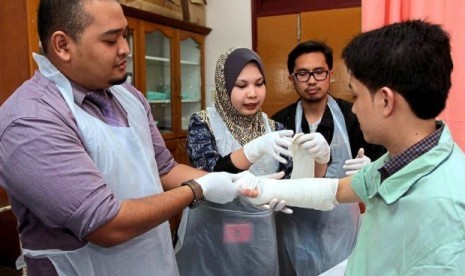 Dari kiri ke kanan, Dokter Arif, Masri and Mohammed Ulil saat memeriksa pasien di Hospital Sultanah Nur Zahirah in Kuala Terengganu, Malaysia.