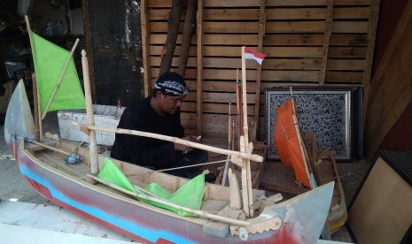 Darmin (37 tahun) seorang perajin miniatur perahu mainan tradisional di Rumah Berdikari, Desa Karangsong, Kabupaten Indramayu, sedang membuat perahu mainannya.