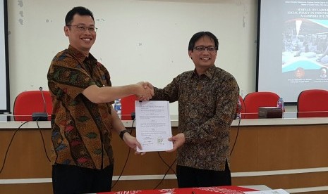 Dekan FISIP UGM Erwan Agus Purwanto (kiri) dan Direktur Umum dan SDM BPJS Ketenagakerjaan Naufal Mahfudz bersalaman seraya menunjukkan naskah kerja sama kedua lembaga di kampus UGM, Yogyakarta, Jumat (27/1).