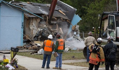 Demolition crews and Hillsborough County Fire Department watch as the house, where Jeffrey Bush was swallowed by a sinkhole, is demolished in Seffner, Florida March 3, 2013. 