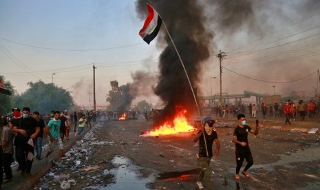 Demonstran antipemerintah melakukan pembakaran dan menutup jalan di Baghdad, Kamis (3/10).