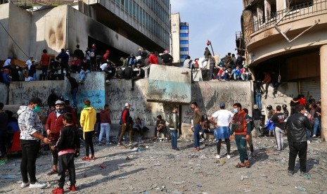 Demonstran berkumpul di dekat penghalang yang dipasang pasukan keamanan untuk menutup Jalan Rasheed saat bentrokan di Baghdad, Irak, Rabu (27/11).