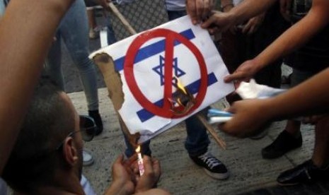 Demonstran di Barcelona, Spanyol membakar plakat bergambar bendera Israel dalam unjuk rasa menentang serangan Israel ke Jalur Gaza, Palestina, Kamis (17/7). Pada saat yang sama, gencatan senjata diberlakukan di Gaza.