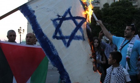 Demonstran di Yunani, Kamis (24/7) membakar bendera Israel sebagai tanda protes terhadap agresi militer ke Gaza.