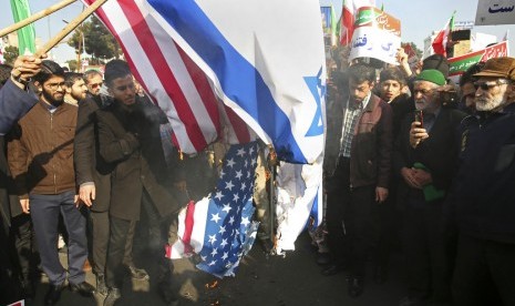 Demonstran Iran membakar bendera AS dan Israel di Mashhad, Iran, Kamis (4/1).