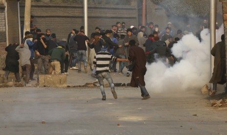 Demonstran Kashmir Syiah berlindung dari asap gas air mata, saat protes terhadap Arab Saudi di Srinagar, Kashmir India, Minggu (3/1).