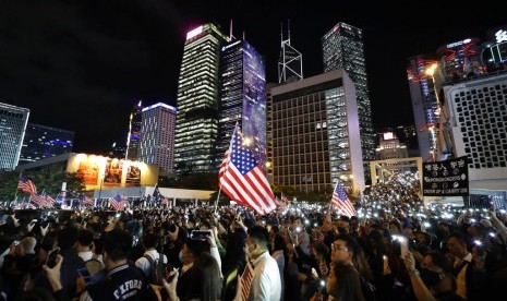 Demonstran memegang bendera AS di Hong Kong, Kamis malam (28/11). Demonstran merayakan tindakan Presiden AS Donald Trump yang menandatangi undang-undang yang mendukung otonomi Hong Kong. 