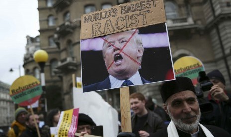 Demonstran memegang papan menunjukkan ketidaksukaannya pada Donald Trump dalam sebuah parade pengungsi di London.