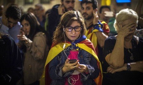 Demonstran mendengarkan pidato Presiden Katalan Carles Puigdemont di luar Palau Generalitat di Barcelona, Spanyol, Sabtu, 21 Oktober 2017.