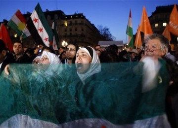 Demonstran menggelar aksi unjuk rasa di Balai Kota Paris, Paris, Kamis (15/3), untuk mendukung rakyat Suriah dalam perayaan satu tahun perlawanan mereka terhadap rezim pemerintahan Bashar al-Assad. 