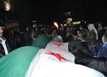 Demonstran menggelar long march dengan membawa bendera Suriah dalam aksi demontrasinya menentang rezim Presiden Bashar Assad di Kedssaya, Damascus, Suriah, Sabtu (4/2) malam. 