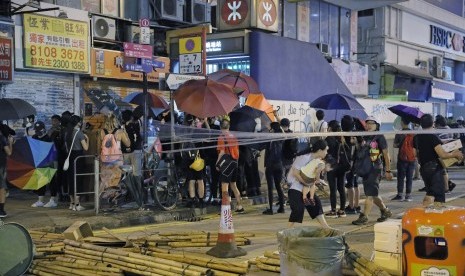   Demonstran menggunakan payung untuk menutupi dirinya saat menutup jalan di Mong Kok, Hong Kong, Jumat (6/9).