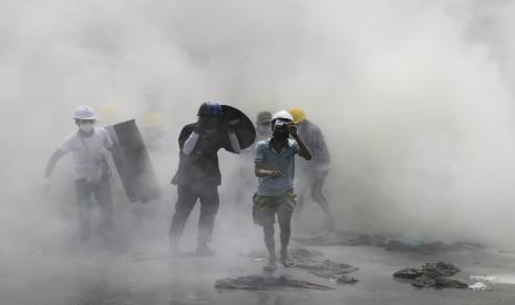 Demonstran menyelamatkan diri dari kepungan gas air mata saat melakukan protes terhadap kudeta militer di Yangon, Myanmar.