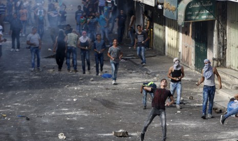 Demonstran Palestina melemparkan batu ke pasukan Israel selama bentrokan di Yerusalem al-Aqsa, di kota Tepi Barat yang diduduki Hebron 29 September 2015.