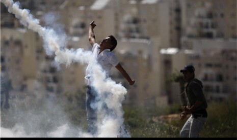 Demonstran Palestina melemparkan kembali tabung gas air mata yang dilepaskan tentara Israel saat aksi demonstrasi menentang pendudukan Israel di Tepi Barat, Ramallah, Jumat (13/4). 