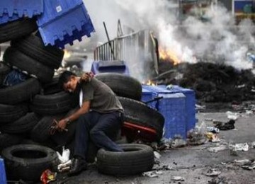 Demonstran berlindung di balik barikade ban bekas.