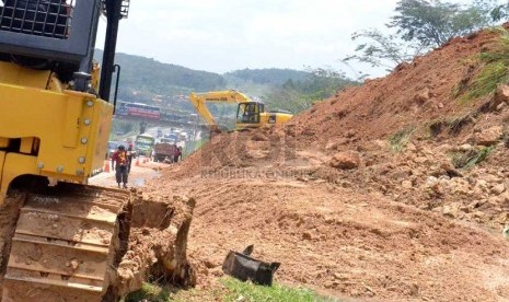  Dengan menggunakan alat berat, petugas membersihkan jalan dari sisa tanah longsor di Tol Cipolarang km 100 jalur Bandung-Jakarta, Rabu (13/2).  (Republika/Maman Suherman)