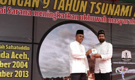 Deputi bidang pencegahan dan kesiapsiagaan BNPB, Dodi Ruswandi (kiri) menyerahkan bahan sosialisasi pengurangan risiko bencana tsunami kepada Wakil Gubernur Aceh Muzakkir Manaf pada acara renungan sembilan tahun tsunami di Taman Ratu Safiatuddin, Banda Ace