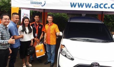 Deputy Chief Sales ACC Ezar Kumendang (kiri) dan Chief Operation Officer ACC Anton Rusli (baju oranye) menyerahkan satu unit mobil Toyota Sienta kepada konsumen bernama Puteri di sela acara Bazaar Sienta di Kantor ACC, Jakarta Selatan, Sabtu (22/10).