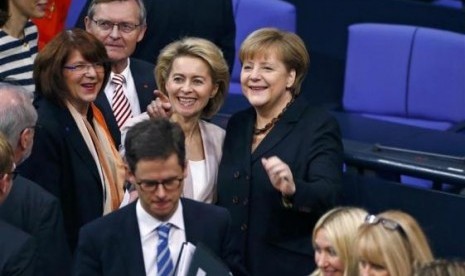 Designated Defence Minister Ursula von der Leyen (center), gestures as she stands beside German Chancellor Angela Merkel (right), during a meeting of the Bundestag, the lower house of parliament, to elect the German Chancellor, in Berlin December 17, 2013.