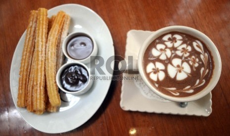 Di kafe-kafe Kota Madrid, Spanyol. hidangan churros bisa ditemukan dengan cocolan saus coklat juga segelas coklat panas.