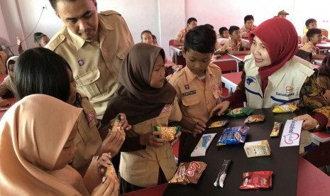 Dian Astriana, Corporate Communication Head GarudaFood (kerudung merah) dan Herri Susanto Guru SD Kampung Sawah 02 (seragam pramuka) mengajak siswa-siswi untuk praktik cara membaca label pada kemasan produk GarudaFood