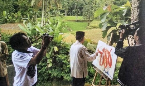 Didin Sirodjudin AR tengah melukis kaligrafi.