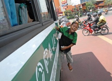 Dimas Ramadhan (11) bekerja sebagai kondektur Bus Kopaja di kawasan Kalibata-Kramatjati, Jakarta, Kamis (19/1). (Republika/Aditya Pradana Putra)