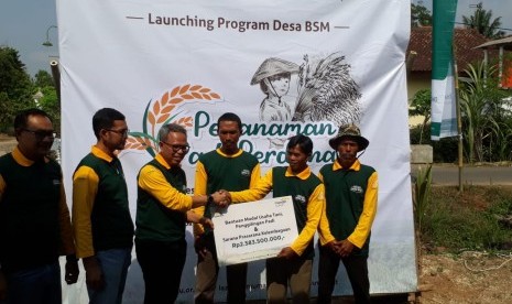 Direktur Bank Mandiri Syariah (BSM) Putu Rahwidhiyasa (ketiga dari kiri) memberikan bantuan uang tunai secara simbolis dalam program Desa Berdaya Sejahtera Mandiri, di Desa Rejo Asri, Kecamatan Seputih Raman, Lampung Tengah, Jumat (26/10). 