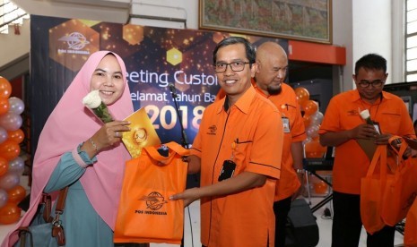 Direktur Jasa Keuangan PT Pos Indonesia Ihwan Sutardiyanta menyerahkan souvenir kepada pelanggan pertama yang datang ke Kantor Pos pusat di Kota Bandung, Selasa (2/1). Mengawali kegiatan di 2018, direksi PT Pos Indonesia menggelar kegiatan sapa pelanggan dan karyawan.