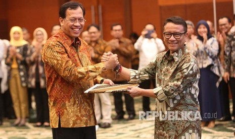 Direktur Jenderal Pajak Kementerian Keuangan yang baru  Robert Pakpahan (kiri) berjabat tangan dengan pejabat lama Ken Dwijugiasteadi saat serah terima jabatan di kantor Kementerian Keuangan (Kemenkeu), Jakarta, Kamis (30/11). 