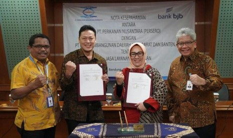 Direktur Konsumer dan Ritel bank bjb Suartini (kedua kanan) dan Direktur Keuangan, SDM dan Umum Perinus Henda Tri Retnadi (kedua kiri) menunjukkan MoU terkait kerja sama permodalan nelayan di Menara Bank BJB, Kota Bandung, Jumat (11/10). Penandatanganan MoU disaksikan oleh Direktur Operasional dan Pemasaran Perinus J Ronald Abraham Tanamal (kiri) dan Dirut Bank BJB Yuddy Renaldi (kanan).