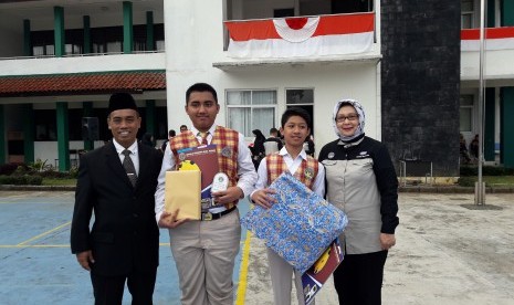 Direktur Pendidikan Sekolah Bosowa Bina Insani (SBBI) Sudirman (kiri) dan Kepala Hubungan Kelembagaan & PR SBBI Dedeh Soeria Atmadja (kanan) bersama dua siswa berprestasi.