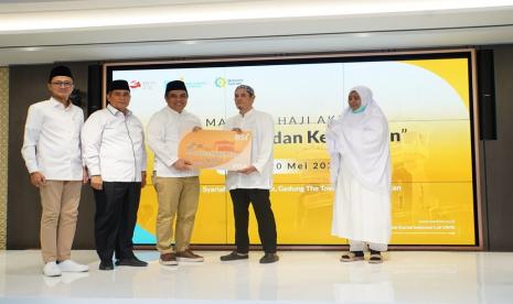 Direktur Sales & Distribution BSI Anton Sukarna (tengah) bersama Direktur Pengelolaan Dana Haji dan Sistem Informasi Haji Terpadu (Dirjen PHU) Kemenag Jaja Jaelani (kedua kiri) dan SVP Islamic Ecosystem BSI M. Syukron Habiby (kiri) menyerahkan Kartu Debit Haji Indonesia kepada salah satu calon jemaah Haji Indonesia dari KBIH Al-Hasanah saat acara Manasik Akbar yang digelar di The Tower, Jakarta, Sabtu (20/5/2023).