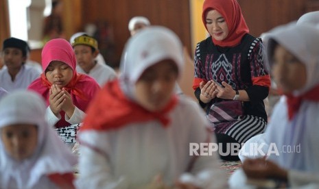 Direktur SDM Pertamina Nicke Widyawati (kanan) berdoa bersama dengan sejumlah anak yatim peserta acara Khataman Alquran di Kantor Pusat Pertamina, Jakarta, Kamis (7/12). 