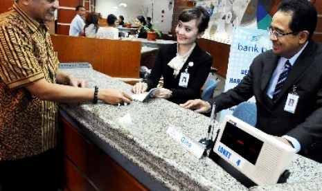  Direktur Utama Bank BJB Bien Subiantoro (kanan) mendampingi teller melayani nasabah yang melakukan transaksi keuangan pada Hari di Bank BJB, Jalan Naripan Bandung.