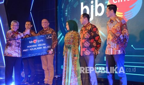 Direktur Utama Bank BJB Yuddy Renaldi (kiri) menyerahkan hadiah Paket Perjalanan Religi program BJB Cinta Guru kepada perwakilan guru, di Kota Bandung, Jumat (14/2).