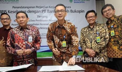 Direktur Utama Bank Syariah Bukopin Saidi Mulia Lubis (tengah), menandatangani naskah kerja sama bersama Direktur Keuangan dan Investasi BPJS Kesehatan Kemal Imam Santoso (kedua kiri), di Jakarta, Kamis (20/9). 