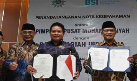 Direktur Utama Bank Syariah Indonesia Hery Gunardi (tengah), Ketua Umum PP Muhammadiyah Haedar Nashir (kanan), dan Menteri Koordinator Bidang Pembangunan Manusia dan Kebudayaan Muhadjir Effendy (kiri) menunjukkan berkas Nota Kesepahaman antara BSI dengan PP Muhammadiyah tentang pemanfaatan produk jasa dan layanan perbankan syariah usai penandatanganan di Gedung PP Muhammadiyah, Jakarta, Kamis (11/8/2022). PT Bank Syariah Indonesia Tbk (BSI) melakukan kerja sama dengan PP Muhammadiyah untuk membantu pelaku UMKM yang ada di bawah naungan PP Muhammadiyah agar bisa naik kelas (up scale) dan menumbuhkan minat masyarakat yang ingin menjadi wirausaha, serta guna meningkatkan inklusifitas dan penetrasi keuangan syariah di Indonesia. 