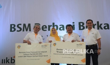 Direktur Utama Bank Syariah Mandiri (BSM) Agus Sudiarto (kiri) dan Komisaris Utama BSM Ventje Rahardjo (kanan) foto bersamam usai simbolis menyerahkan bantuan kepada Bupati Garut Rudi Gunawandi (kedua kanan) untuk korban banjir bandang pada acara 17 tahun 