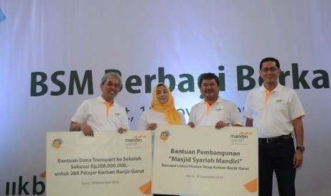 Direktur Utama Bank Syariah Mandiri (BSM) Agus Sudiarto (kiri) dan Komisaris Utama BSM Ventje Rahardjo (kanan) foto bersamam usai simbolis menyerahkan bantuan kepada Bupati Garut Rudi Gunawandi (kedua kanan) untuk korban banjir bandang pada acara 17 tahun 