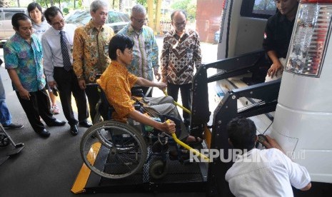 Direktur Utama Bank Syariah Mandiri (BSM), Agus Sudiarto (tengah) menyaksikan penyandang disabilitas naik ke mobil akses jelang mudik berkah bareng BSM 2016 di Gedung Pusat Bank Syariah Mandiri, Jakarta, Kamis (30/6). (Republika/Agung Supriyanto)