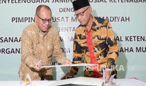 Direktur Utama BPJS Ketenagakerjaan Agus Susanto (kiri) menandatangani nota kesepakatan bersama dengan Ketua Umum PP Muhammadiyah Haedar Nashir di Jakarta, Rabu (5/4). 