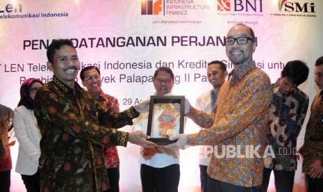 Direktur Utama PT LEN Telekomunikasi Indonesia Raden Wahyu Pantja Gelora (kiri) memberikan cinderamata kepada Presiden Direktur PT Indonesia Infrastructure Finance (IIF) Airsudono Soerono seusai penandatanganan kerjasama pembiayaan Proyek Palapa Ring II 